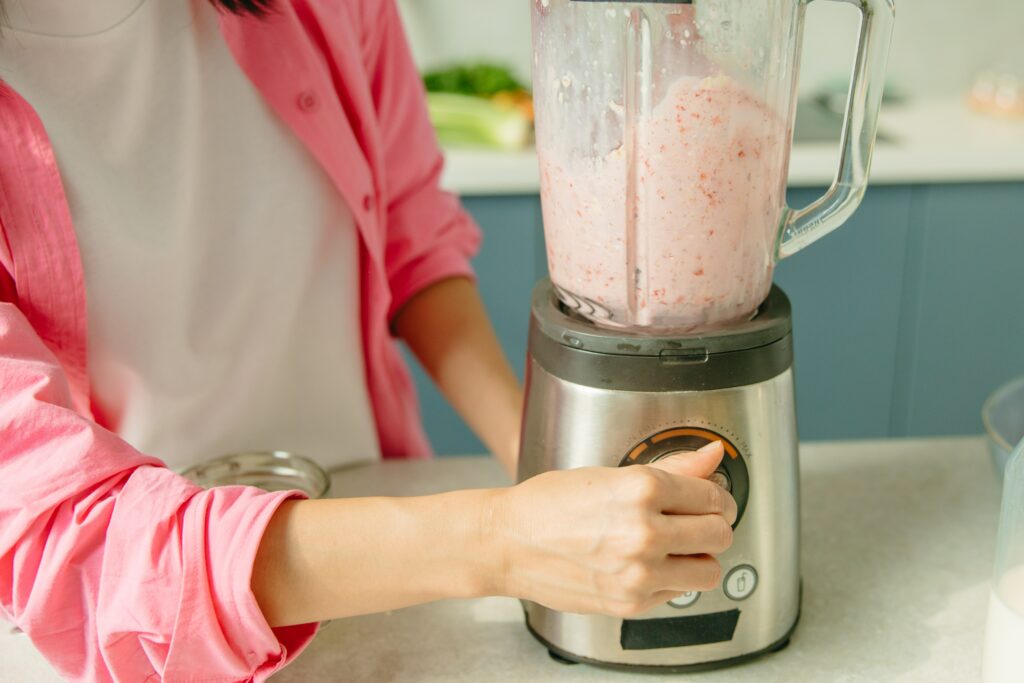 A female making a smoothie with an electric kitchen appliance